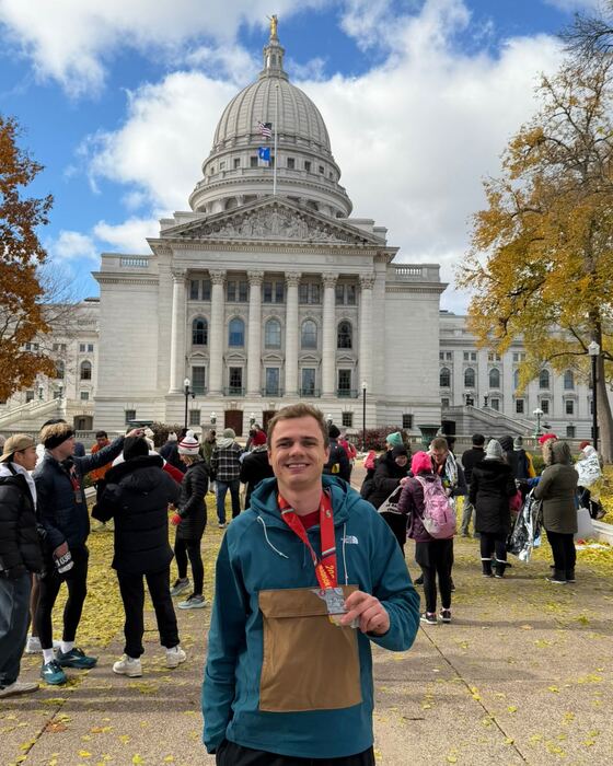 Nikolaj Hindsbo holding a finisher's medal in front of the Wisconsin State Capitol